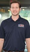 A man in a navy polo shirt with a JES logo stands smiling indoors.