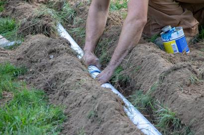 A close-up of hands installing pipes in the ground.