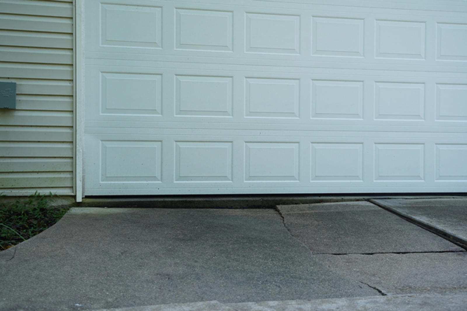 Cracked and uneven driveway with a garage.