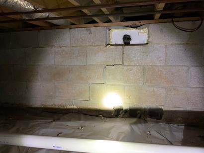 Cracks and damage vent on crawlspace cinderblock wall.