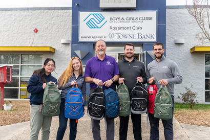 Group holding backpacks in front of Boys & Girls Clubs building.