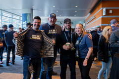 Four people in matching shirts smile and pose together at an indoor event.