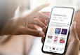 Person using a smartphone to browse books on an app, with a blurred background.