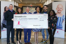 Group holding a large check for St. Jude Children's Research Hospital donation at a business lobby.