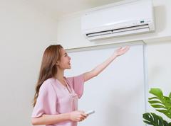 woman stands beneath air vent, feeling the air