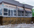 Building with visible foundation and pilings, featuring large windows and modern design elements.