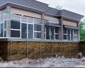 Building with visible foundation and pilings, featuring large windows and modern design elements.