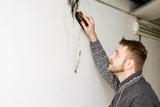 man scraping mold off of basement wall