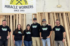 Group of six people wearing matching shirts, standing under a sign that says "Tuesday Morning Miracle Workers Since 1993.