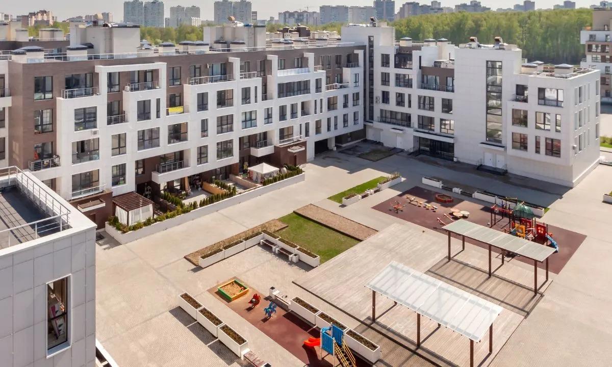 Modern apartment complex with a spacious courtyard featuring playground equipment and minimal landscaping.