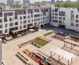 Modern apartment complex with a spacious courtyard featuring playground equipment and minimal landscaping.