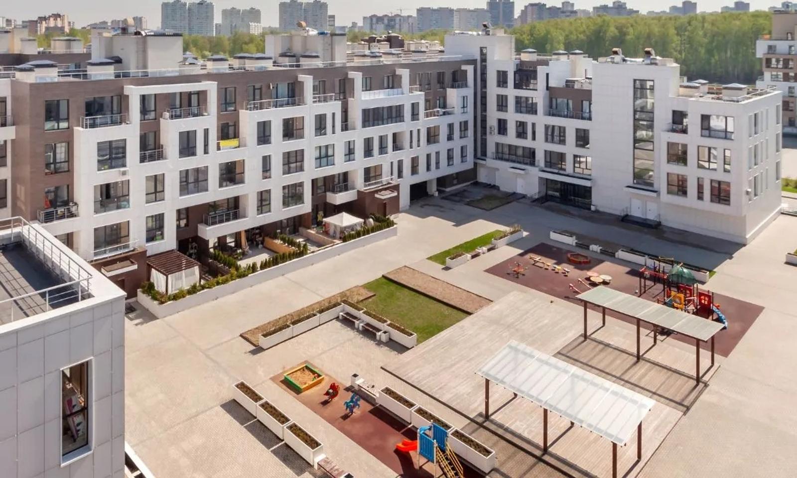 Modern apartment complex with a spacious courtyard featuring playground equipment and minimal landscaping.