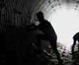 Silhouette of a person climbing inside a large, illuminated tunnel of corrugated metal—an airport infrastructure repair case study.