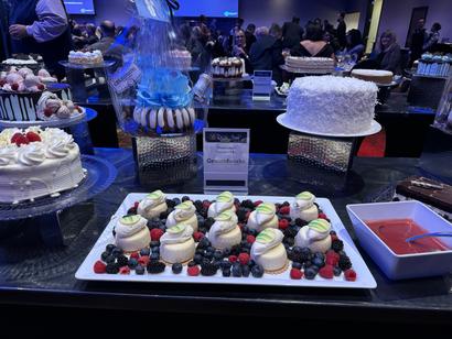 A dessert display with pastries, cakes, macarons, berries, and a sauce dish at a formal event.