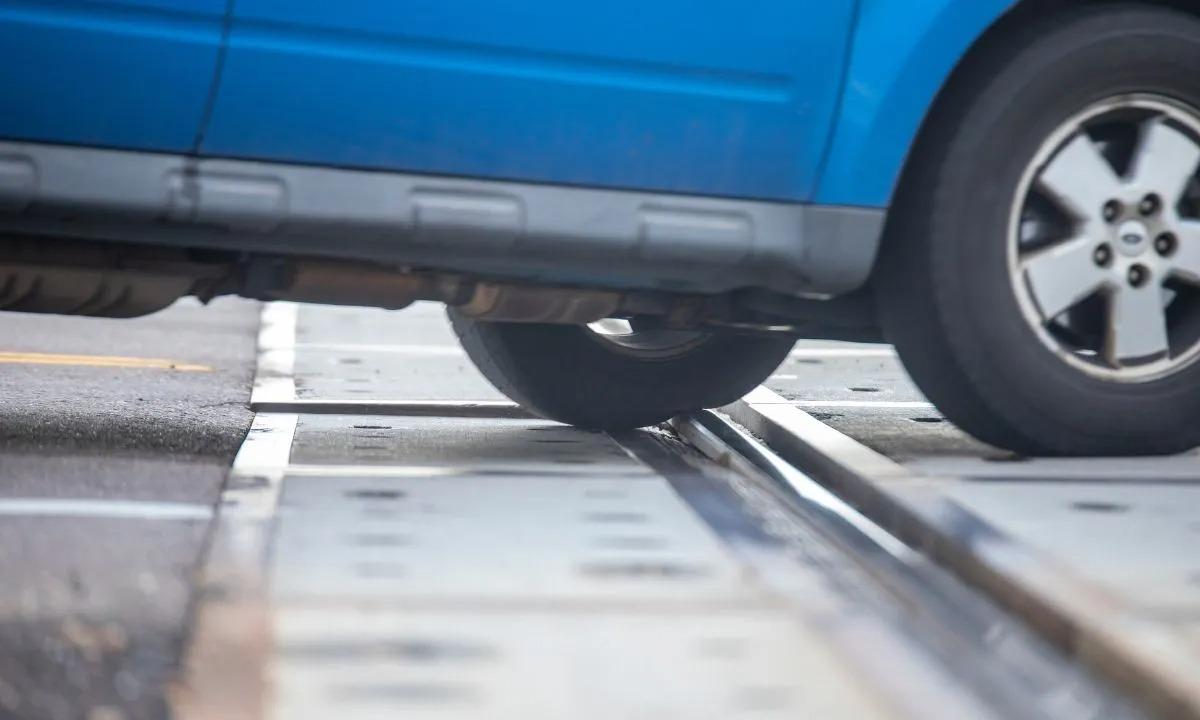 Close-up of a blue vehicle's wheel stuck on a railway track at a crossing.