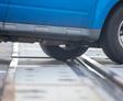 Close-up of a blue vehicle's wheel stuck on a railway track at a crossing.
