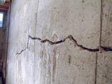 A large, jagged crack runs horizontally across an old, weathered concrete wall.