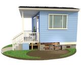 A small blue house with a front porch, exposed foundation, and green grass surrounding it.