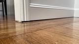 White wall slightly separated over a wooden floor, revealing a small gap.