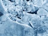 Close-up of cracked ice with overlapping translucent sheets and intricate frost patterns.