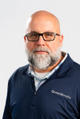 Man with a gray beard and glasses wearing a "Groundworks" jacket against a plain background.