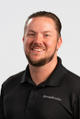 Smiling man with short hair and beard in a black "Groundworks" shirt against a light background.