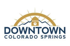 Logo of Downtown Colorado Springs with a clock tower, sun, and mountains.