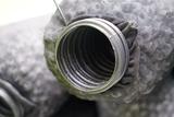 Close-up of a black, corrugated plastic pipe wrapped in a mesh fabric material.
