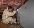 Groundworks crew member installing insulation in a crawl space