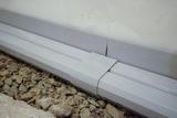 Close-up of a perimter drain on top of rough gravel, with a visible joint where two pieces meet.