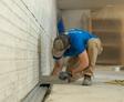 worker installing basement drainage