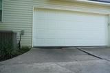 White garage door with a slight gap at the bottom—perfect spot to consider concrete lifting solutions.