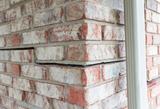 Close-up of a brick wall with a large horizontal crack indicating structural damage.