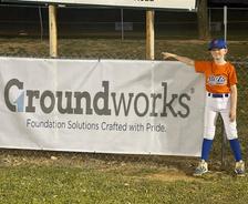 San Antonio Canyon Lake Little League player standing near banner