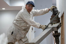 A worker in protective gear operates construction equipment indoors, taking measures to prevent soil erosion, with gloves and safety glasses.