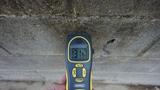 A handheld moisture meter reads 31.9% against a rough concrete wall, suggesting possible waterproofing needs.