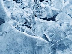 Close-up of cracked, textured ice with frosty patterns.