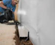 crew member installing interior drainage in a basement