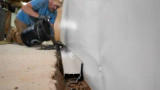 crew member installing interior drainage in a basement