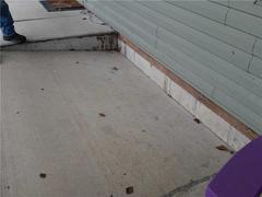 Sinking concrete porch by a house wall.