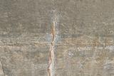 A close-up of a concrete surface with a visible vertical crack and some white staining.