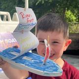 a child with a handmade boat created at Groundworks Fort Wayne's Kids' Craft Zone at the Dragon Boat Races
