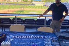 Groundworks member standing at booth in front of baseball field