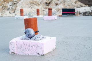 An orange pipe on a construction site with pink foam blocks.