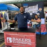 an employee of Groundworks, formerly Baker's Waterproofing, standing in a company booth at the 2025 Running of the Wools