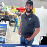 An employee with Groundworks, formerly Baker's Waterproofing, stands in a company booth at the Food Truck Festival in Pittsburgh