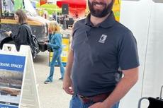 An employee with Groundworks, formerly Baker's Waterproofing, stands in a company booth at the Food Truck Festival in Pittsburgh