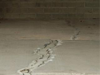 cracks in a concrete floor slab adjacent to a brick wall. this floor need floor leveling with polyurethane injection from Groundworks