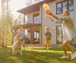 family and dog playing frisbee in front yard of house