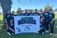 players with the Resto Athletics – YMCA Softball Team, Northern Nemesis, stand next to a banner with their name and the FSM logo
